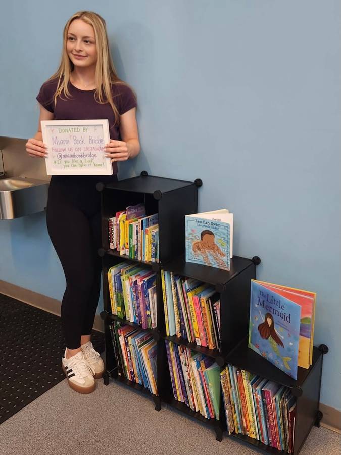 Ella Brandt standing beside the new Gibson Park mini-library bookshelf