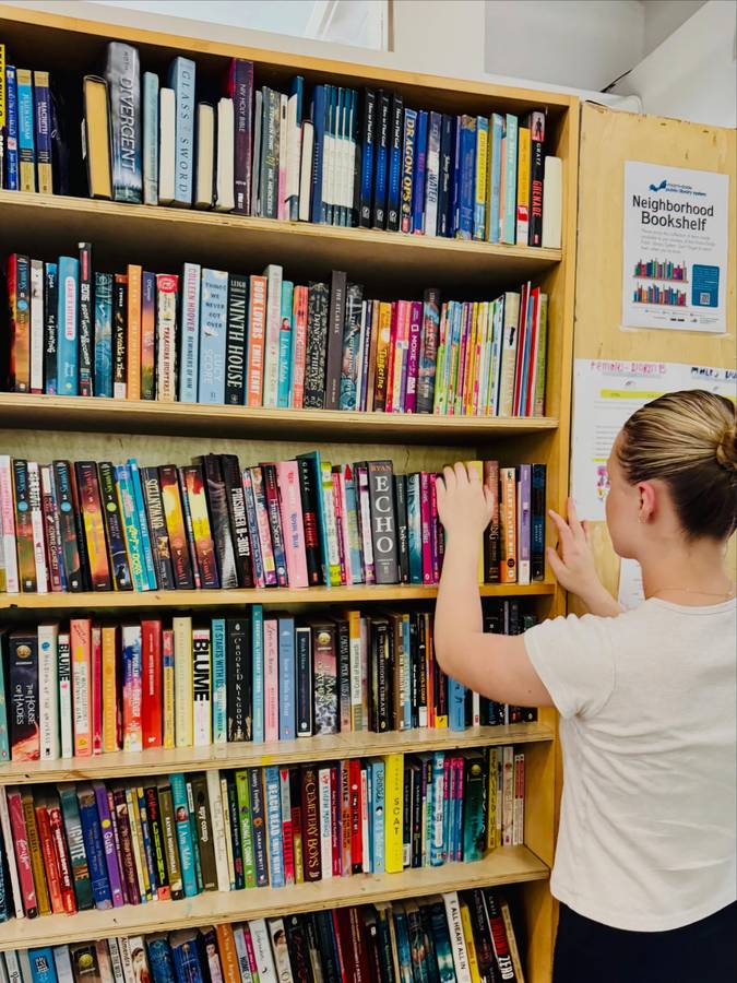 Arranging books on a tall library bookshelf at Miami Bridge