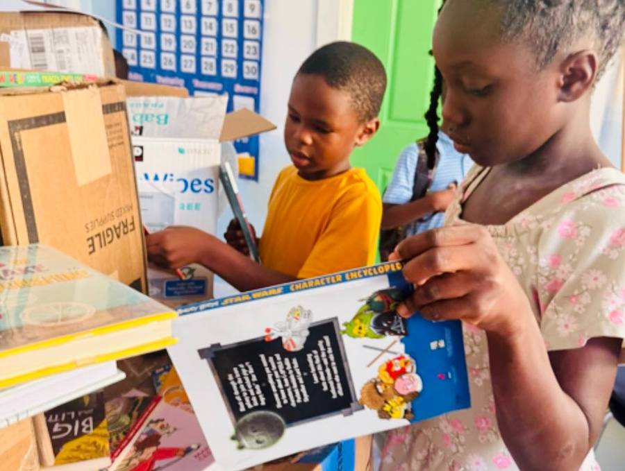 Two children at EEO in Eleuthera unboxing donated books and a puzzle