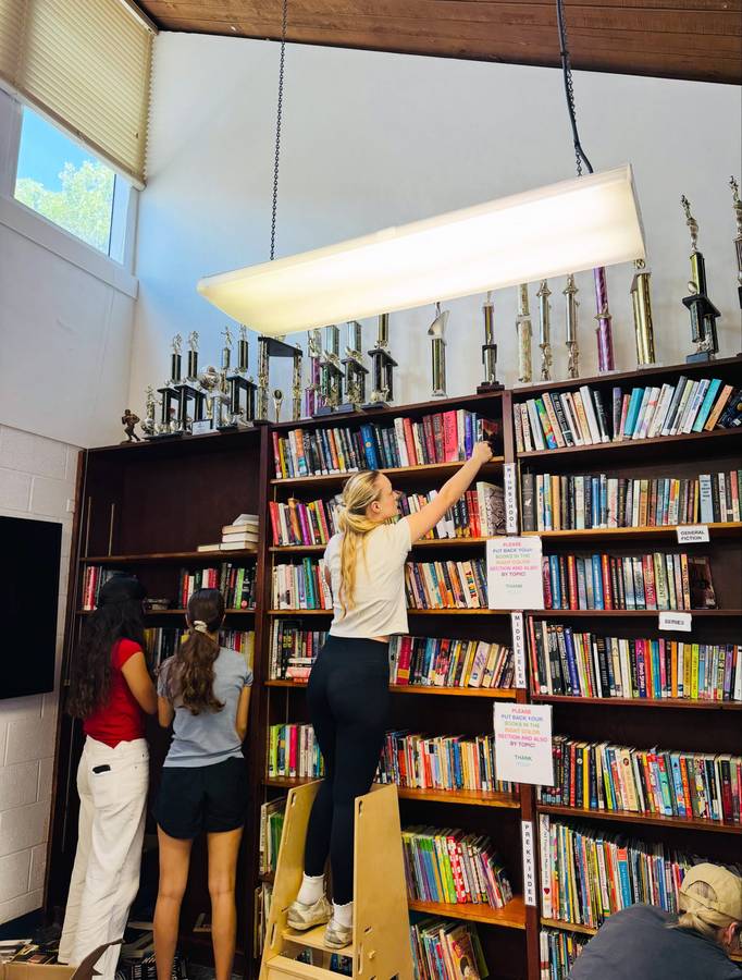 Volunteers stocking tall shelves in the new TACOLCY Center library